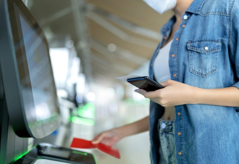 young asian female woman casual cloth hand show passport and ticket to check in  travel vacation at staff airline kiosk,safety travel asian female with mask at airport terminal checking in for flight